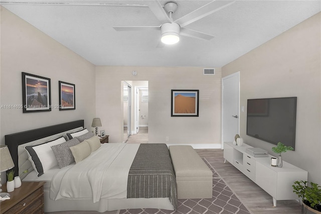 bedroom with ceiling fan, hardwood / wood-style flooring, and a textured ceiling