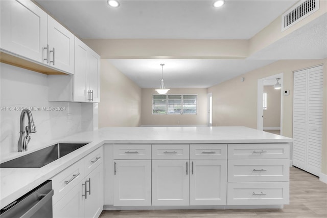 kitchen featuring stainless steel dishwasher, kitchen peninsula, white cabinetry, and sink