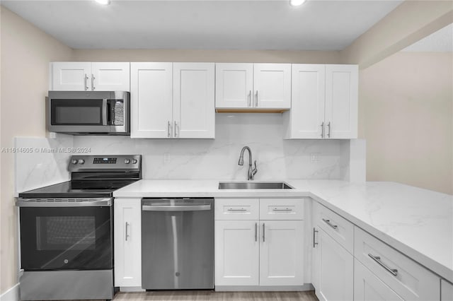 kitchen with appliances with stainless steel finishes, sink, tasteful backsplash, and white cabinetry