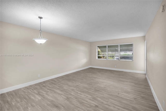 empty room with a textured ceiling and hardwood / wood-style floors