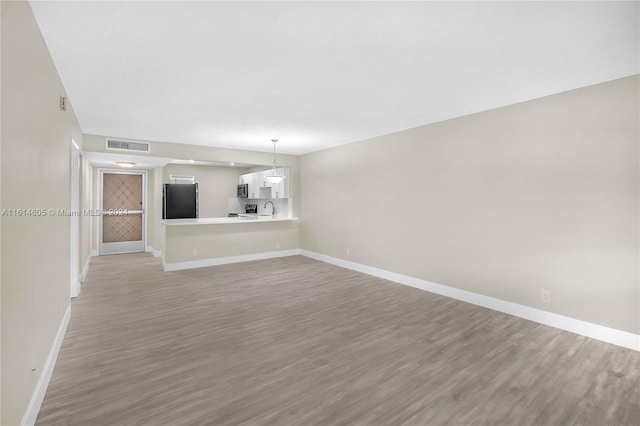 unfurnished living room featuring hardwood / wood-style floors and sink