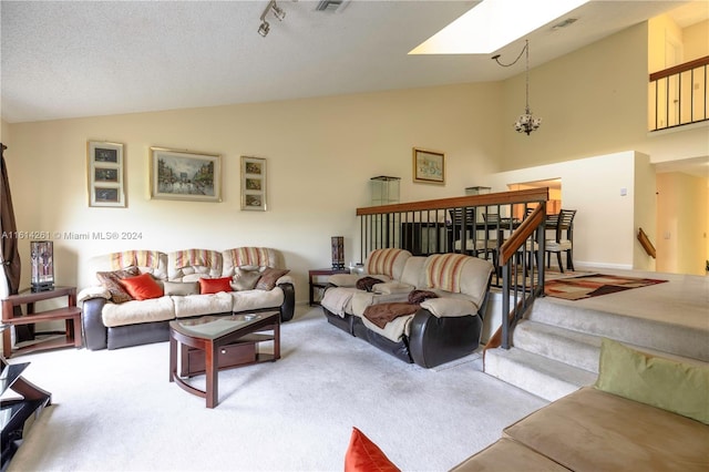 living room featuring a skylight, a textured ceiling, high vaulted ceiling, a chandelier, and carpet floors