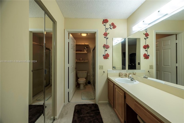 bathroom featuring vanity, tile patterned flooring, toilet, a textured ceiling, and walk in shower