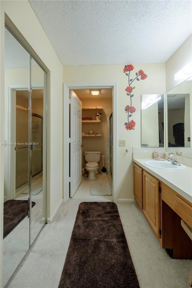 bathroom featuring vanity, toilet, an enclosed shower, and a textured ceiling