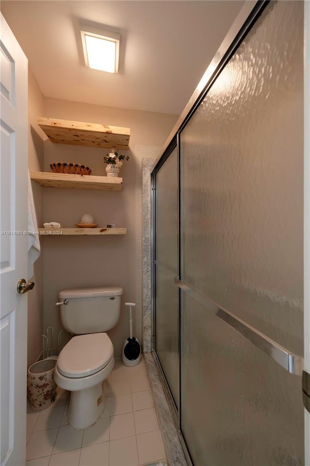 bathroom with toilet, tile patterned floors, and a shower with shower door