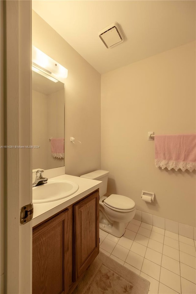 bathroom with toilet, vanity, and tile patterned floors