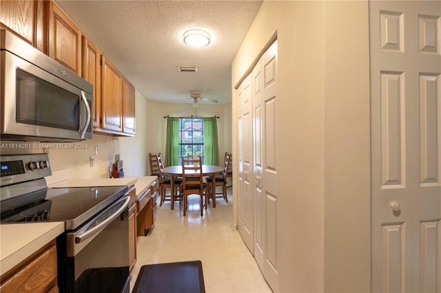 kitchen with appliances with stainless steel finishes, a textured ceiling, and ceiling fan