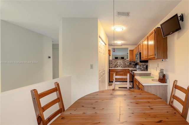 kitchen with a textured ceiling, stainless steel appliances, and tasteful backsplash