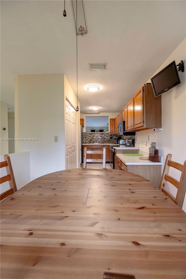 kitchen featuring kitchen peninsula, stainless steel appliances, light hardwood / wood-style floors, hanging light fixtures, and a breakfast bar area