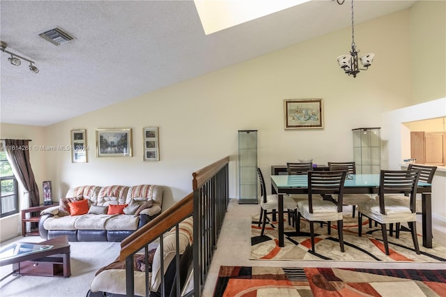 carpeted living room with rail lighting, a notable chandelier, a textured ceiling, and high vaulted ceiling