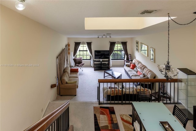 carpeted living room with an inviting chandelier