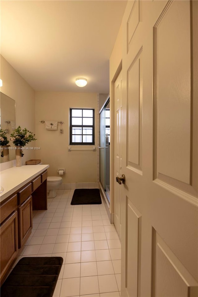 bathroom with tile patterned flooring, vanity, toilet, and a shower with shower door