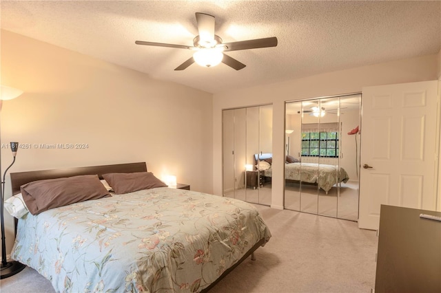 carpeted bedroom featuring ceiling fan, a textured ceiling, and two closets