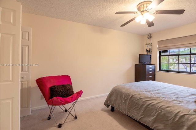 bedroom with ceiling fan, light colored carpet, and a textured ceiling