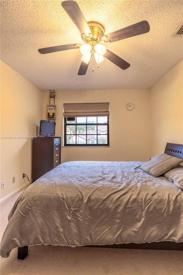 bedroom with a textured ceiling, carpet floors, and ceiling fan