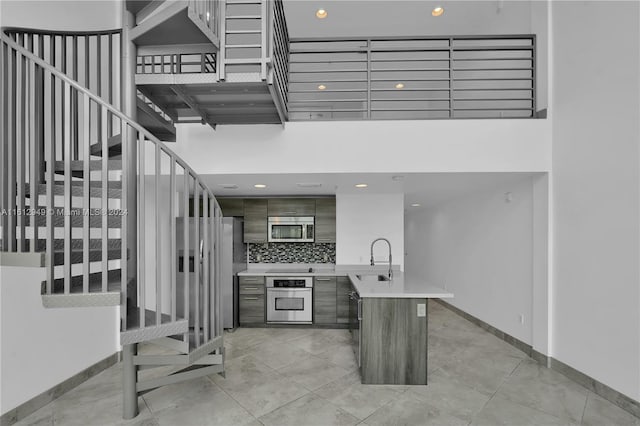 interior space featuring backsplash, appliances with stainless steel finishes, sink, and light tile floors