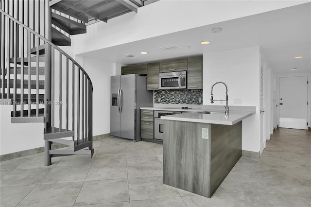 421 Meridian Ave Unit 16, Miami Beach, FL 33139 - kitchen with stainless steel appliances, light countertops, a peninsula, baseboards, and backsplash
