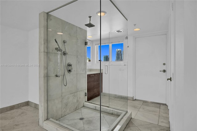 bathroom with a shower with shower door, vanity, and tile floors