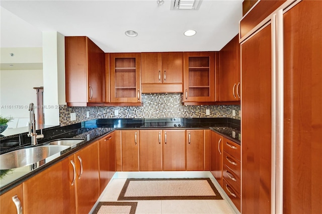 kitchen with backsplash, dark stone counters, black electric stovetop, sink, and light tile patterned floors