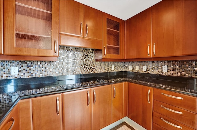 kitchen featuring backsplash, dark stone counters, and black cooktop