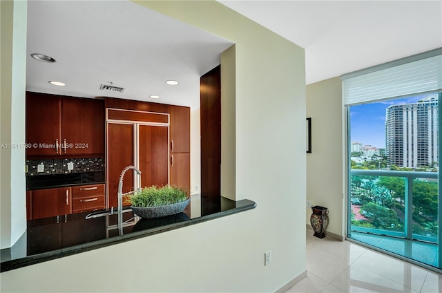 kitchen featuring dark stone counters, sink, paneled built in refrigerator, light tile patterned floors, and tasteful backsplash