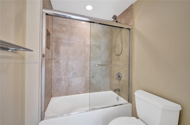 bathroom featuring toilet and bath / shower combo with glass door