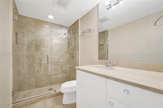 bathroom with tile patterned floors, vanity, toilet, and a shower with door