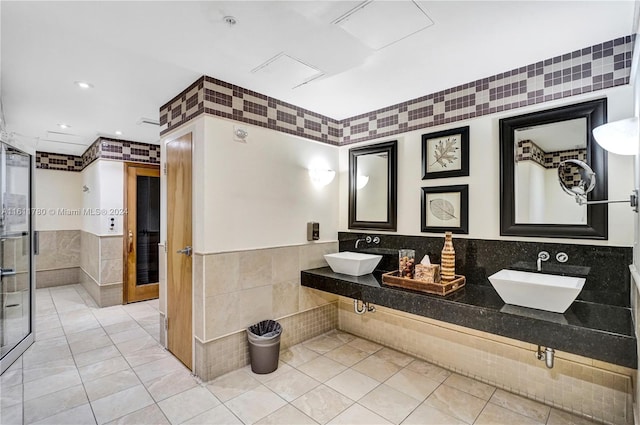 bathroom with tile patterned flooring, tile walls, and sink