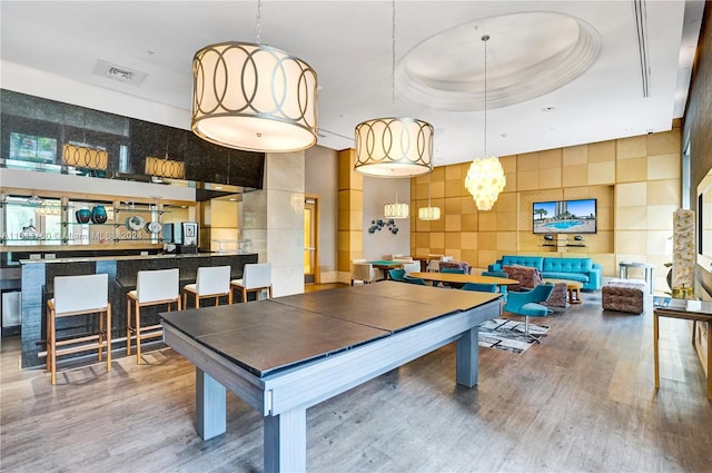 recreation room featuring hardwood / wood-style floors and a raised ceiling