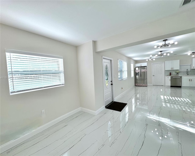 unfurnished living room featuring sink and a notable chandelier