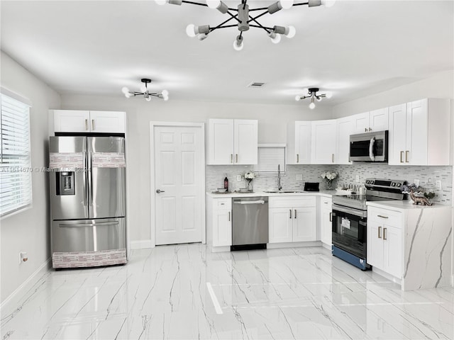 kitchen with white cabinetry, appliances with stainless steel finishes, and a chandelier