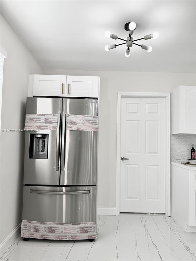 kitchen with stainless steel refrigerator with ice dispenser, tasteful backsplash, and white cabinets