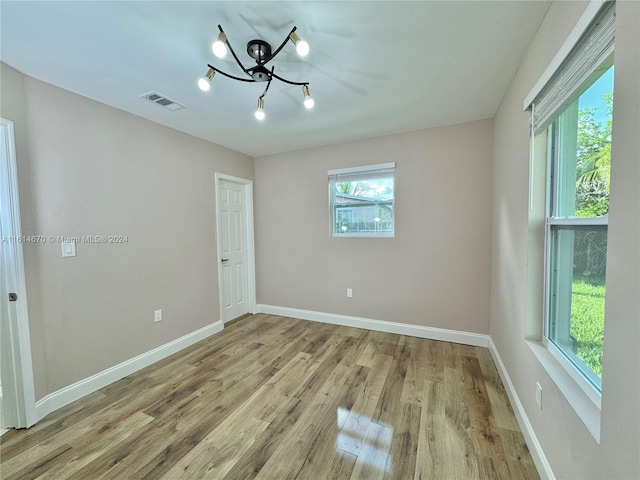 unfurnished room featuring a chandelier and light hardwood / wood-style floors