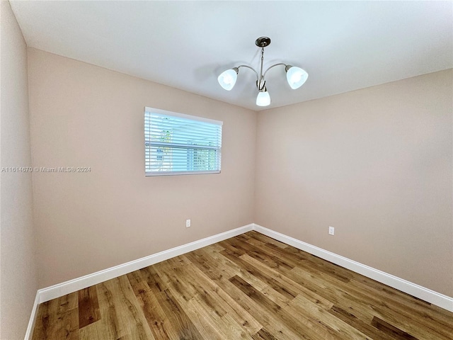 unfurnished room with a notable chandelier and hardwood / wood-style flooring