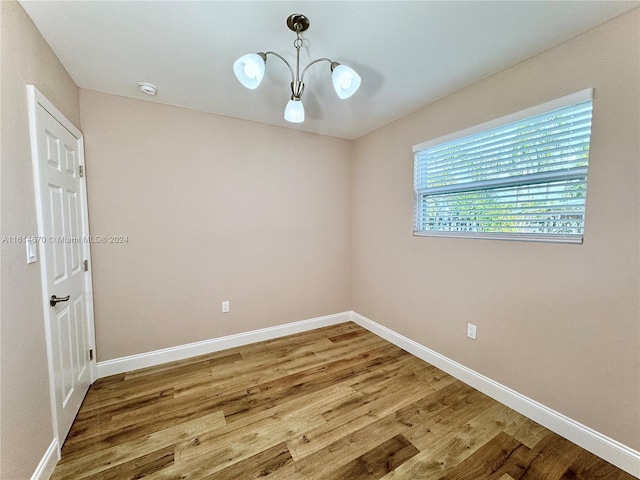 unfurnished room with an inviting chandelier and hardwood / wood-style flooring