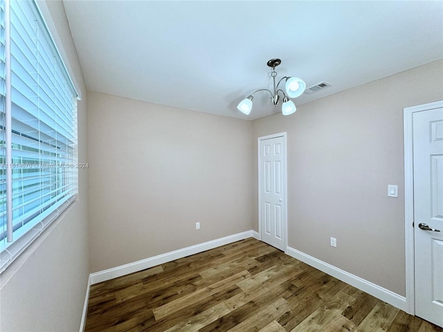 spare room with wood-type flooring and an inviting chandelier