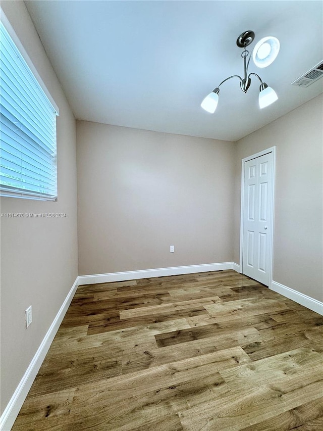 spare room with wood-type flooring and a notable chandelier