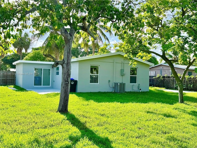 back of property with a lawn, central air condition unit, and a patio area