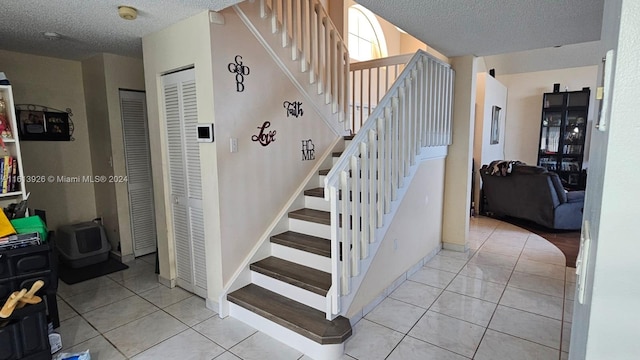 staircase with tile patterned floors and a textured ceiling