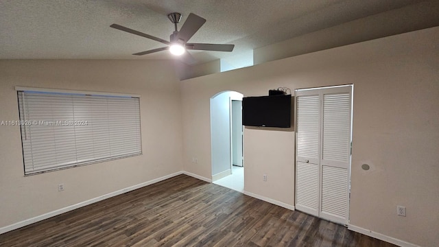 unfurnished bedroom with lofted ceiling, ceiling fan, dark wood-type flooring, a textured ceiling, and a closet