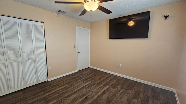 unfurnished bedroom with dark wood-type flooring, a textured ceiling, ceiling fan, and a closet