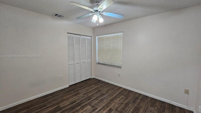 unfurnished bedroom with dark hardwood / wood-style floors, a textured ceiling, ceiling fan, and a closet