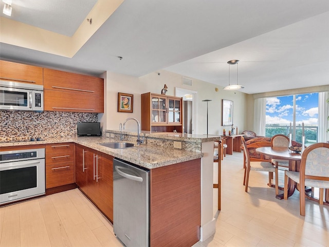 kitchen with appliances with stainless steel finishes, tasteful backsplash, sink, hanging light fixtures, and kitchen peninsula