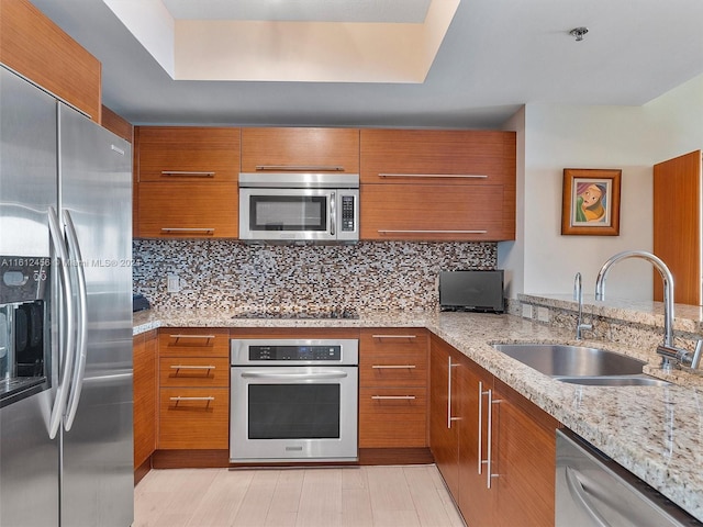 kitchen with decorative backsplash, sink, light stone counters, and stainless steel appliances