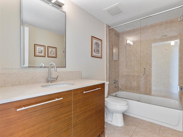 full bathroom featuring toilet, bath / shower combo with glass door, tile patterned floors, and vanity