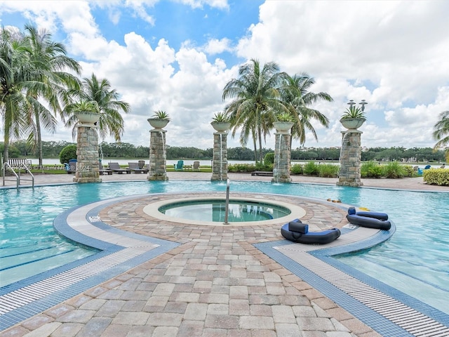 view of pool with pool water feature and a hot tub