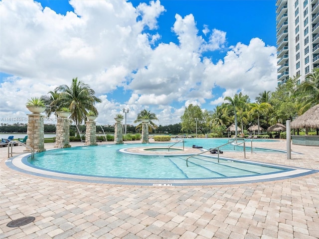 view of swimming pool with pool water feature and a hot tub