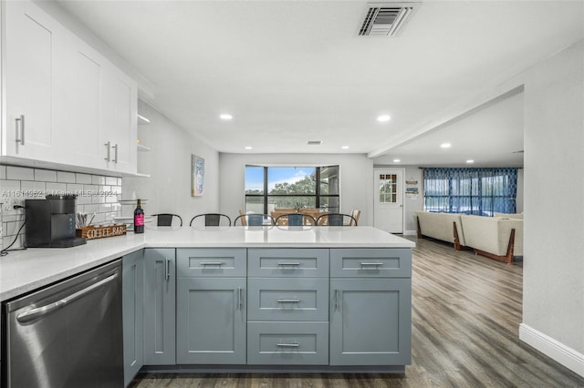 kitchen with kitchen peninsula, white cabinets, stainless steel dishwasher, and gray cabinetry