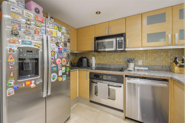 kitchen featuring light brown cabinets, light tile patterned floors, tasteful backsplash, stainless steel appliances, and light stone countertops