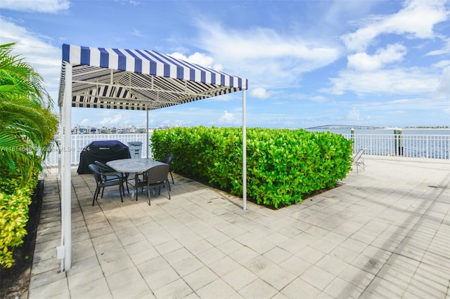 view of patio with a grill and a water view